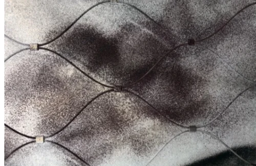 Auf dem Bild ist ein dunkler Hintergrund zu sehen. Davor wird ein Eisenzaun aus dünnen Drähten in Rautenform angedeutet.