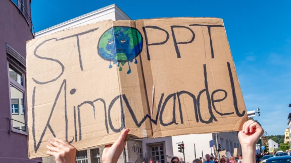 Schild mit trauriger Weltkugel mit Text stoppt Klimawandel